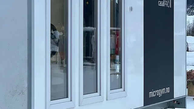 Nærbilde av hvit treningsmodul med tre vinduer og logoen "microgym.no".